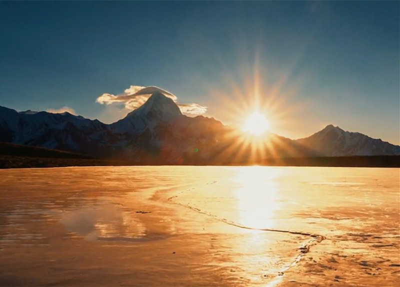 太阳升起的贡嘎雪山头顶帽状云奇观的美景